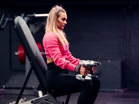Postpartum woman resting in between sets at the gym