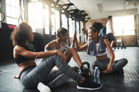 young women giving each other a high five while taking a break at the gym.
