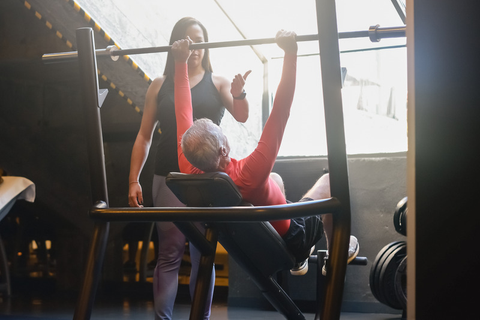 Woman in black tank top looking at a man lifting a bar