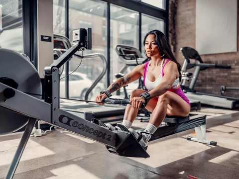 Young woman working out on row machine at gym exercising